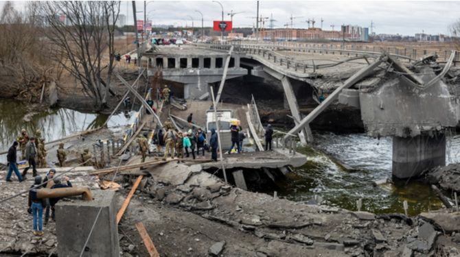 IRPIN, UKRAINE - Mar. 05, 2022: War in Ukraine. People cross a destroyed bridge as they evacuate the city of Irpin, northwest of Kyiv, during heavy shelling and bombing