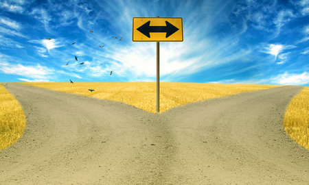 Two roads, road sign ahead with arrows blue sky background. Countryside landscape