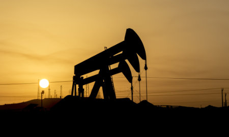 A photo of crude oil pumps silhouetted against the sunset