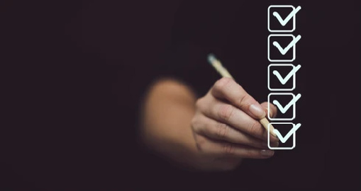 Marking on checklist box isolated on black background. Checklist concept. Hand holding a pencil and checklist isolated on black background with copy