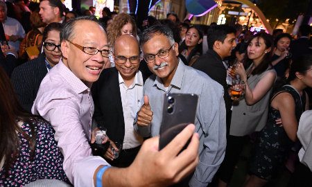 Three delegates at Singapore Convention Week taking a selfie at a reception